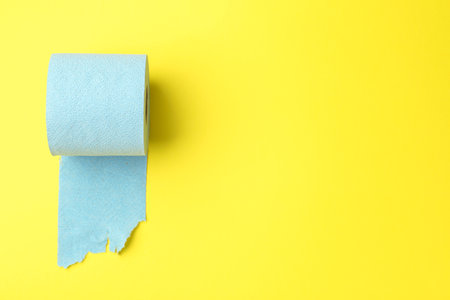 Light blue toilet paper roll on yellow background, top view. Space for textの写真素材
