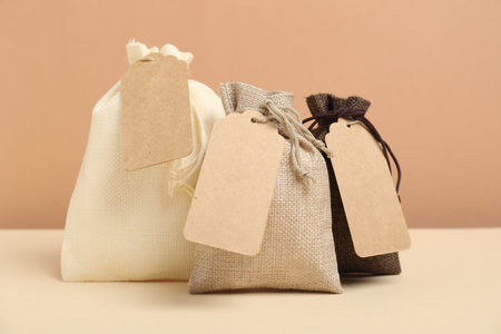 Burlap bags with tags on table against beige backgroundの写真素材