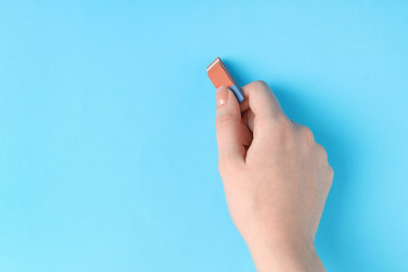 Woman using eraser on light blue background, closeup. Space for textの写真素材