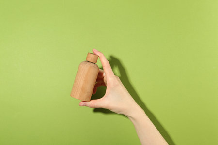 Woman with bottle of serum on green background, closeup. Body care productの写真素材