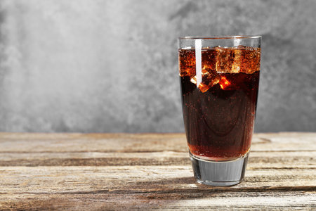 Sweet soda water with ice cubes in glass on wooden table, space for textの写真素材