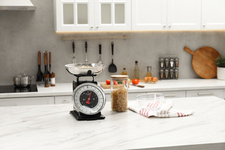 Retro mechanical kitchen scale and raw pasta on white marble table indoorsの写真素材