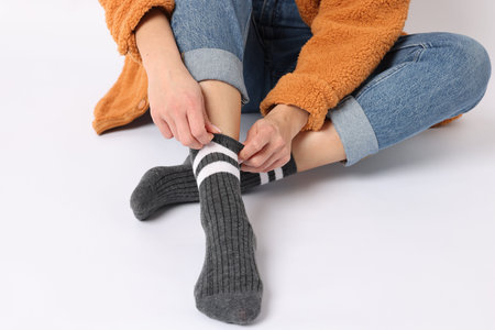 Woman wearing gray socks on white background, closeup