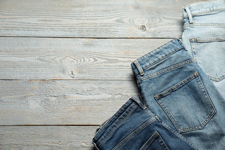 Different stylish jeans on grey wooden background, flat lay. Space for textの写真素材