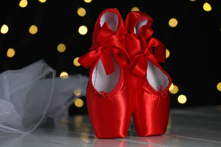 Pair of beautiful pointe shoes and decor on floor against blurred lights. Bokeh effectの写真素材