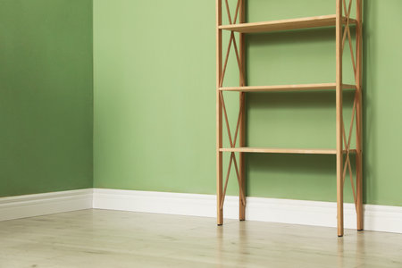 Empty wooden shelving unit near olive wall indoors. Space for textの写真素材