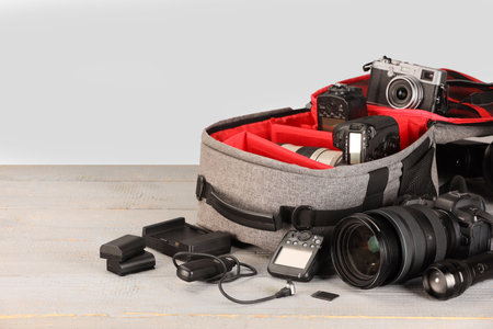 Professional photographer's equipment and backpack on light wooden table. Space for textの写真素材