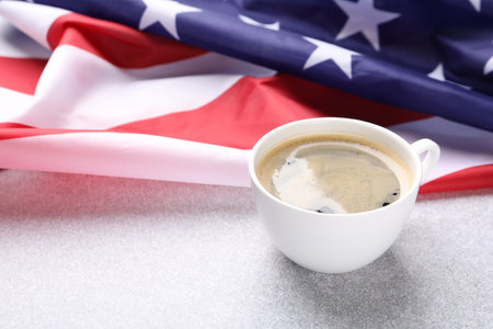 Cup of coffee and American flag on light table. Space for textの写真素材