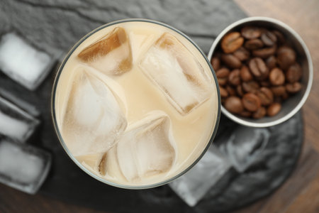 Coffee cream liqueur in glass, ice cubes and beans on wooden table, top viewの写真素材