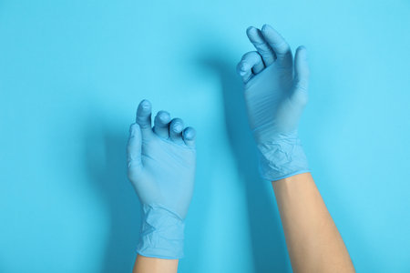 Person in medical gloves on light blue background, closeupの写真素材
