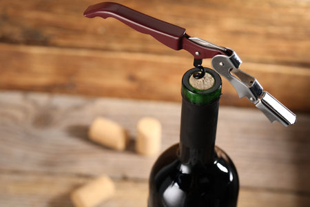 Bottle of luxury wine with corkscrew on blurred background, closeup. Space for textの写真素材