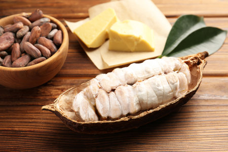 Cocoa pod with beans and butter on wooden table, closeupの写真素材