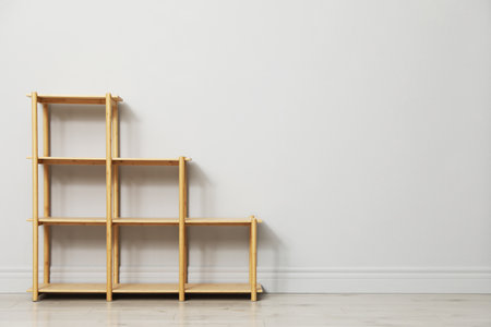 Empty wooden shelving unit near light grey wall indoors. Space for textの写真素材