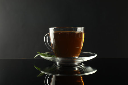 Aromatic tea in glass cup and mint on dark mirror tableの写真素材
