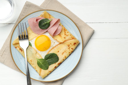 Delicious crepe with egg, ham and water on white wooden table, flat lay. Space for textの写真素材