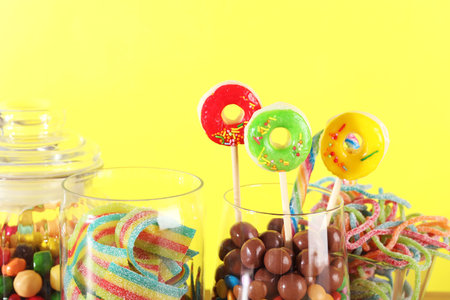 Candy bar. Many different sweets against yellow background, closeup. Space for textの写真素材