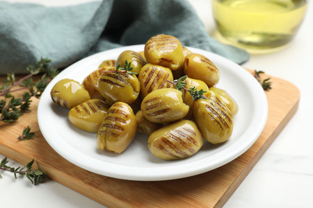 Delicious grilled green olives on white table, closeupの写真素材