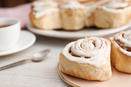 Delicious frosted cinnamon rolls on light wooden table, closeupの写真素材