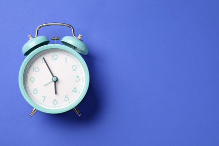 One turquoise alarm clock on blue background, top view. Space for textの写真素材
