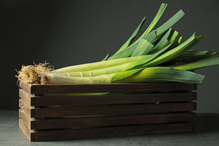 Fresh raw leeks in wooden crate on gray table, closeupの写真素材