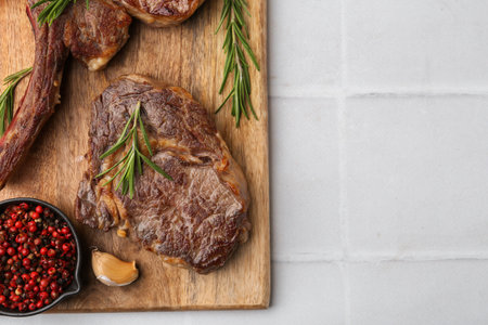 Pieces of beef meat and spices on white tiled table, top view. Space for textの写真素材