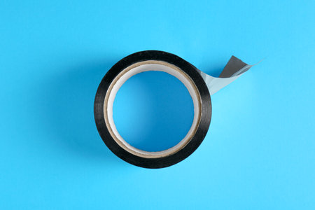 Roll of black adhesive tape on light blue background, top viewの写真素材