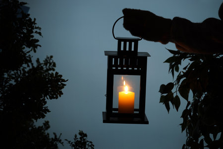 Woman holding Christmas lantern with burning candle in evening, closeupの写真素材