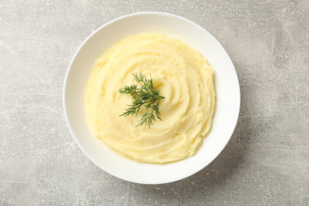 Tasty mashed potato with dill in bowl on gray textured table, top viewの写真素材