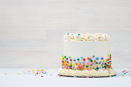 Delicious cake with colorful sprinkles on light table, space for text