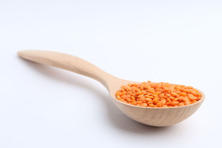 Raw lentils in wooden spoon isolated on whiteの写真素材
