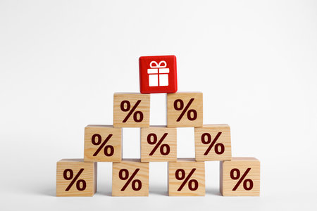 Red cube with gift box image on top of pyramid of other ones with percent signs against white backgroundの写真素材