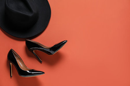 Pair of high heeled shoes and hat on red-brown background, flat lay. Space for textの写真素材