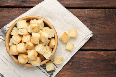 Delicious crispy croutons in bowl on wooden table, top viewの写真素材