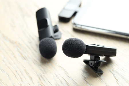 Lavalier microphones and smartphone with wireless receiver on wooden table, closeupの写真素材