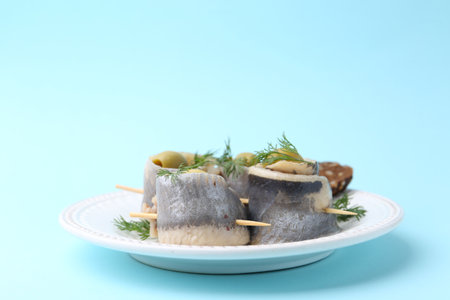 Delicious herring rolls with olives and dill on light blue background, closeupの写真素材