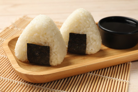 Rice balls (onigiri) and soy sauce on table, closeup. Traditional Japanese dishの写真素材