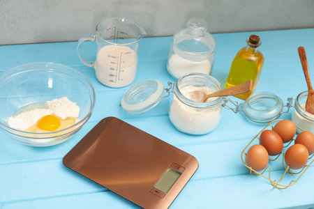 Electronic kitchen scale and different food products on light blue wooden table indoors, closeupの写真素材