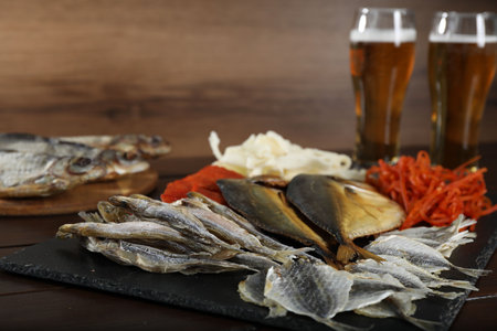 Dried fish snacks and beer on wooden table, closeupの写真素材