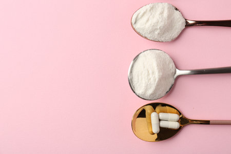 Collagen powder and pills on pink background, flat lay. Space for textの写真素材
