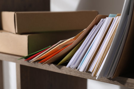 Different paper envelopes and parcels on wooden shelf in post office, closeupの写真素材