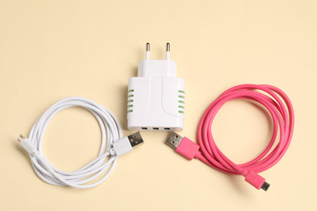 USB power adapter and charge cables on beige background, flat lay