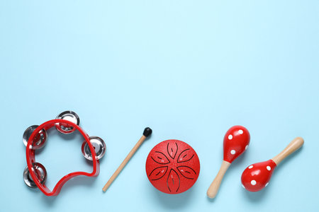 Flat lay composition with different toy musical instruments on light blue background. Space for text