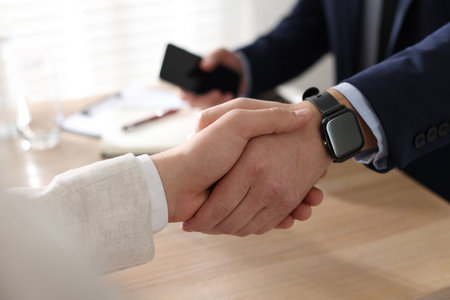 Men shaking hands at wooden table in office, closeupの写真素材