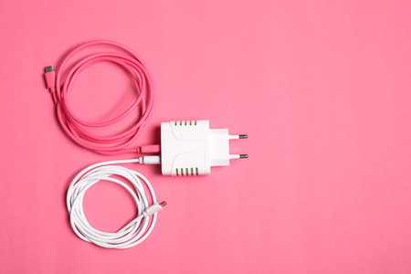 USB power adapter with charge cables on pink background, top view. Space for textの写真素材