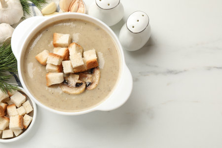 Delicious mushroom cream soup with croutons and ingredients on white marble table, flat lay. Space for textの写真素材