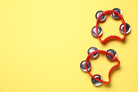 Bright toy tambourines on yellow background, flat lay. Space for textの写真素材