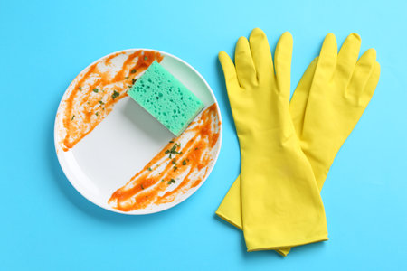 Dirty plate, sponge and gloves on light blue background, flat layの写真素材