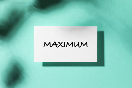 Business card with word Maximum on turquoise background, top view