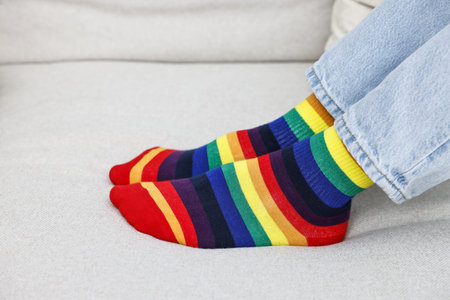 Man wearing socks in colors of LGBT flag on sofa, closeupの写真素材