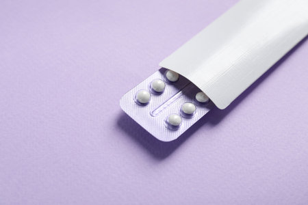 Blister of contraceptive pills in package on lilac background, closeup. Space for textの写真素材